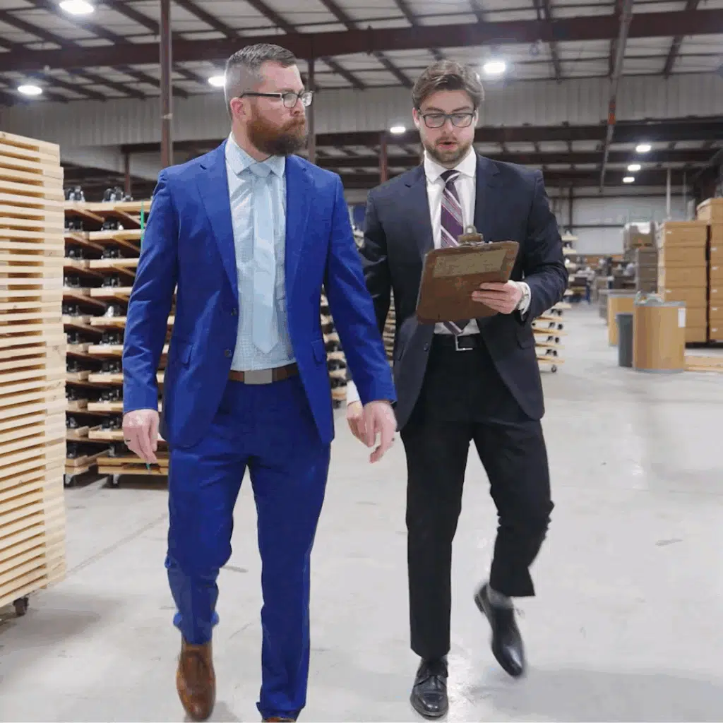 Two men walking through a distribution warehouse holding lumber