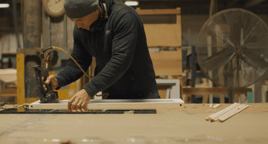 A male carpenter finishing a millwork cabinet panel