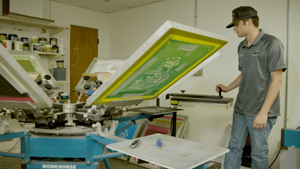 Man operating screen printing equipment in a printing facility