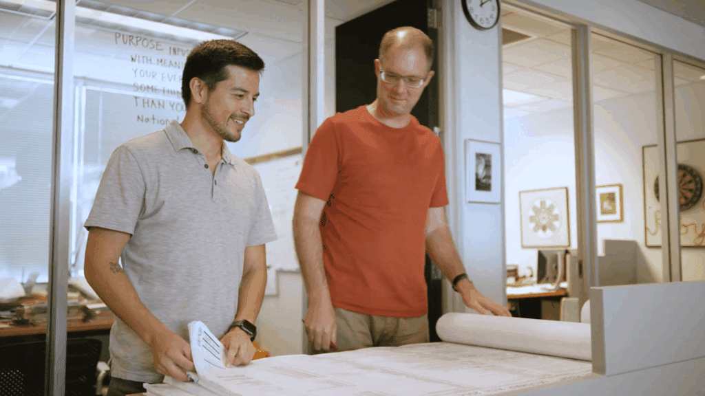 Two male architects looking at design plans and smiling