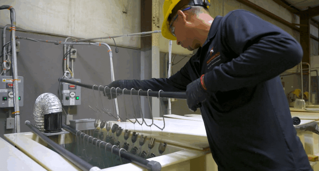 Worker in safety gear performing chemical treatment of metal