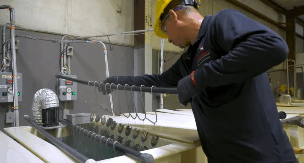 Worker in safety gear performing chemical treatment of metal
