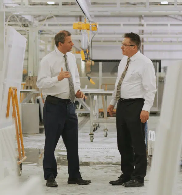 Two businessmen discussing strategy in a manufacturing facility - Cogent Analytics client
