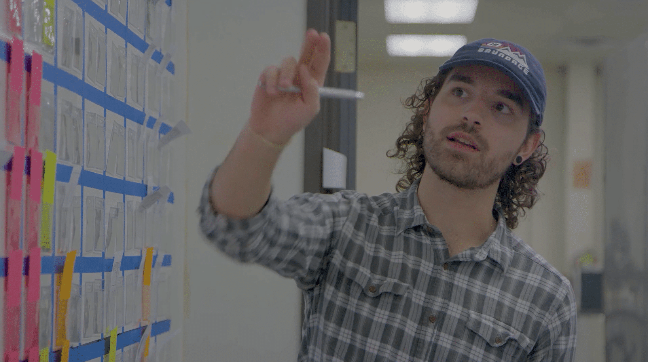 Waggoner Manufacturing in Round Rock, Texas. Young man in hat pointing to info on the walls.