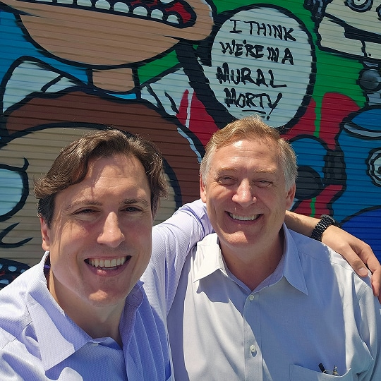 Career development at Cogent Analytics, 2 men smiling in front of a mural