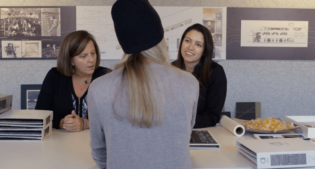 A woman with her back turned to the camera, facing two other women during a consultation