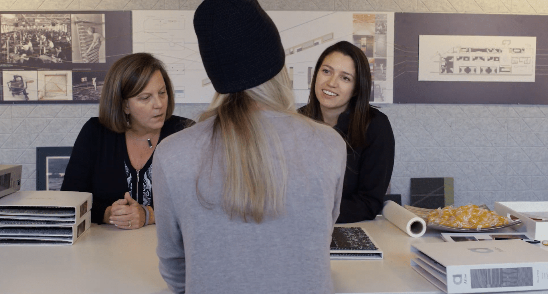 A woman with her back turned to the camera, facing two other women during a consultation