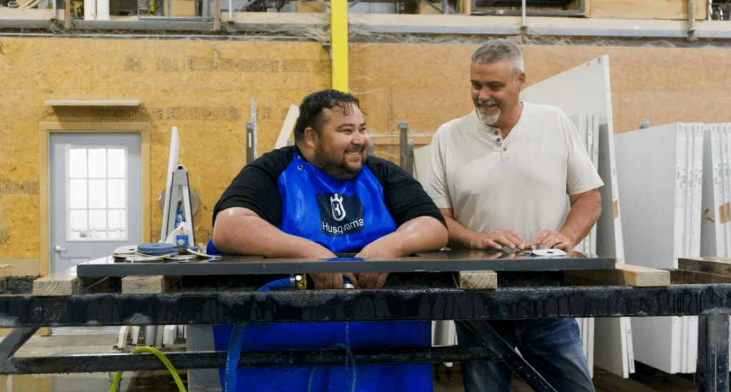 Two men smiling while working on countertop fabrication