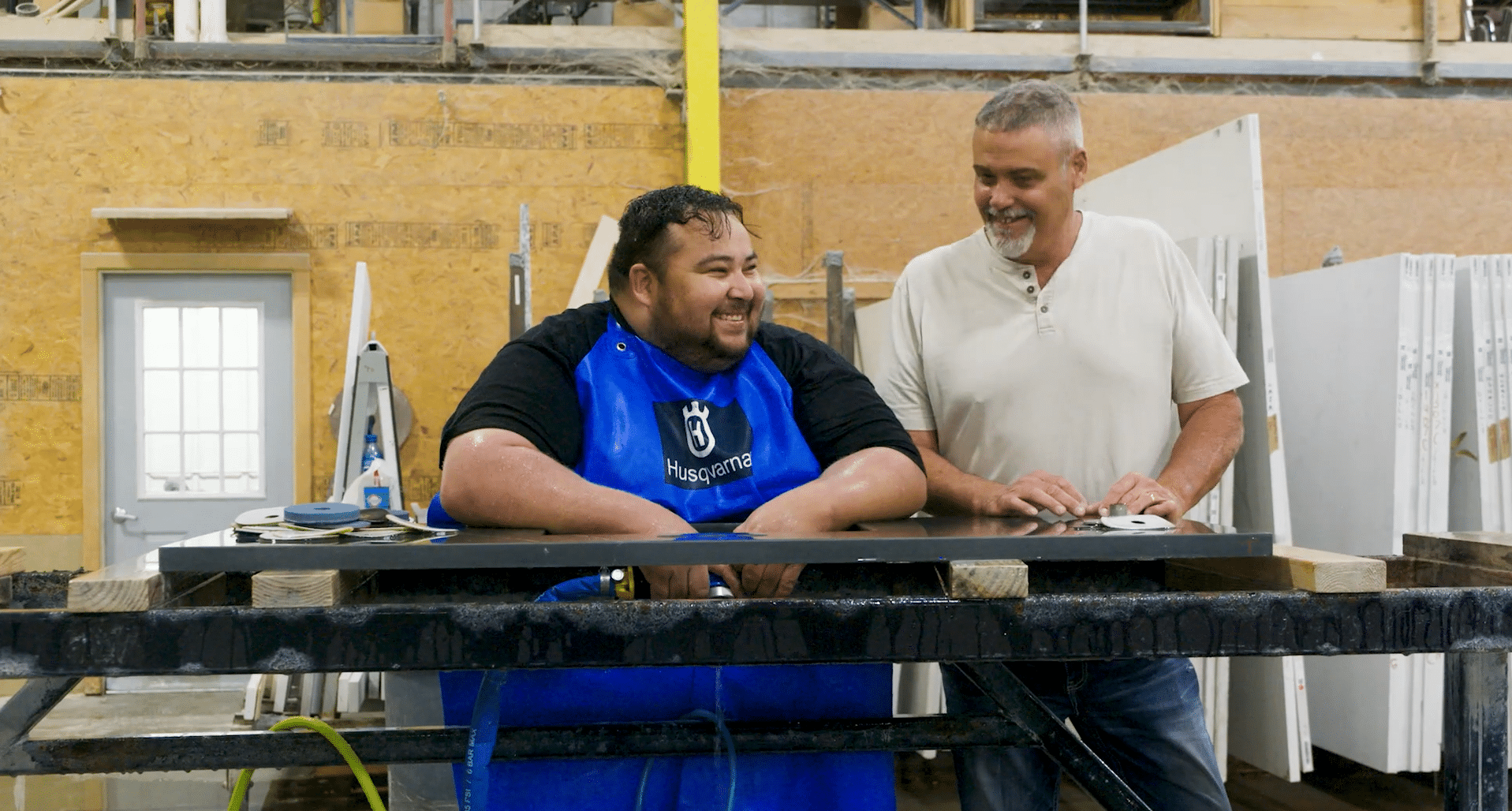 Two men smiling while working on countertop fabrication