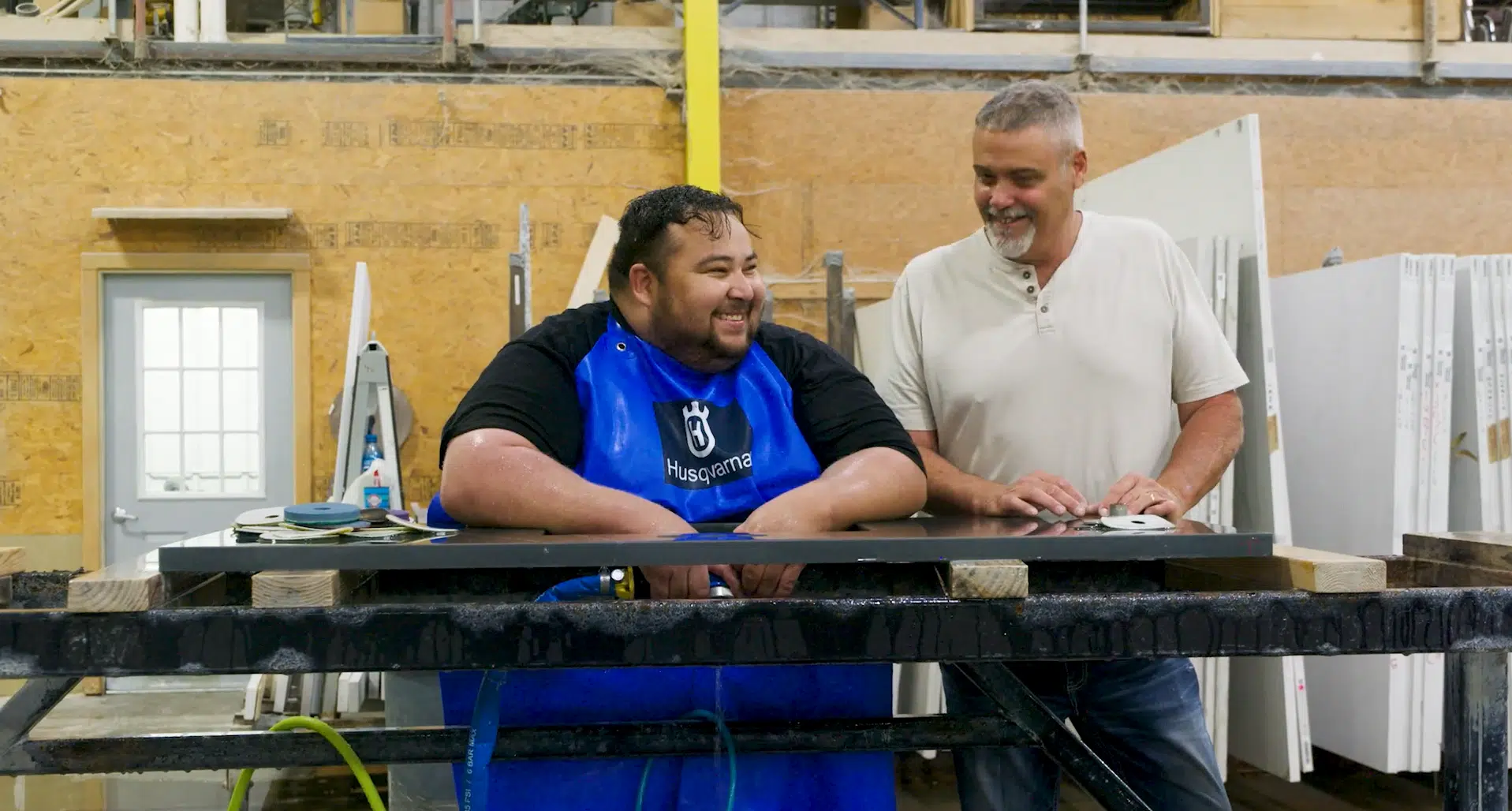 Two men smiling while working on countertop fabrication