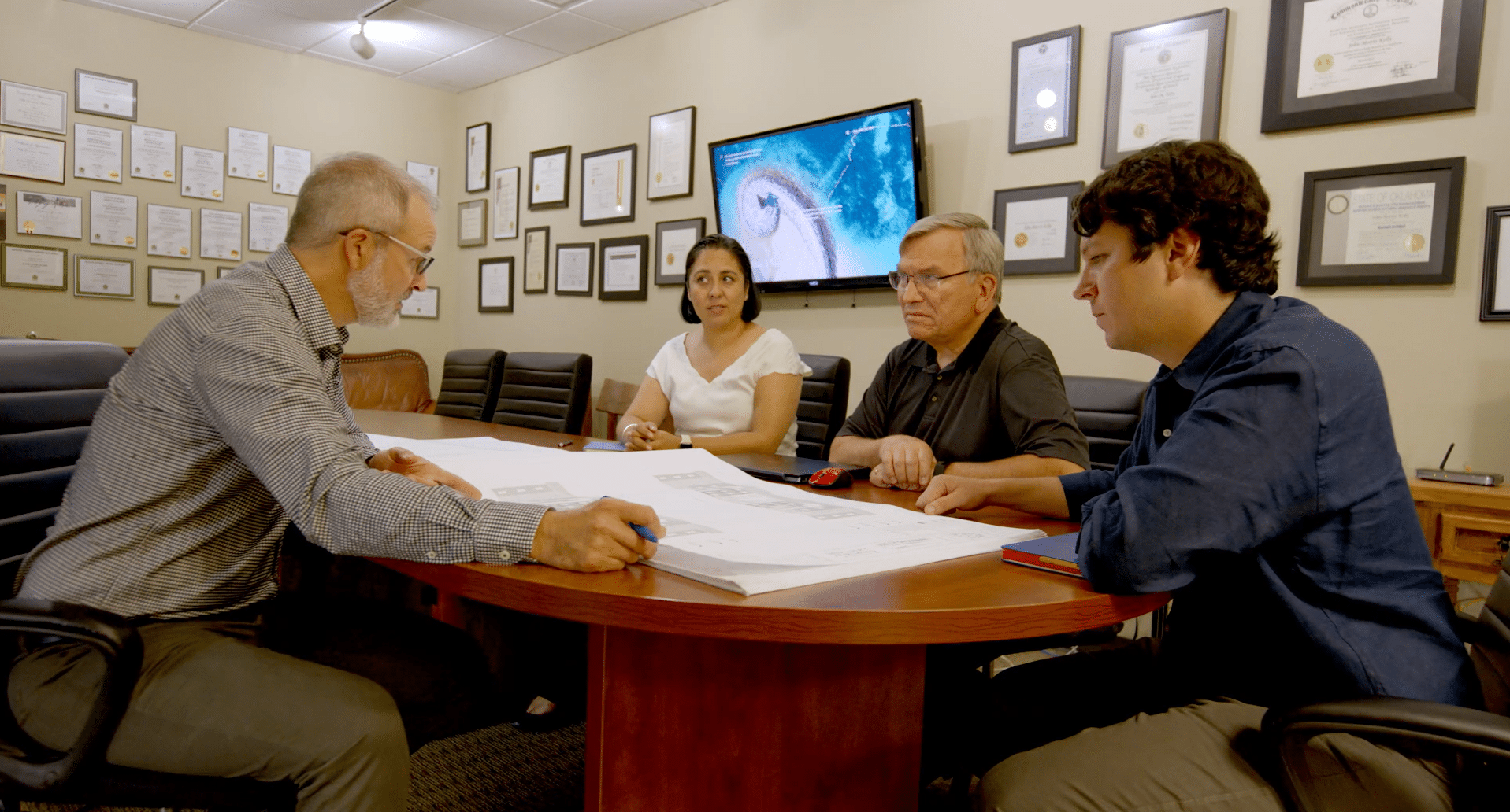 A team of architects looking over plans in a conference room with awards on the wall