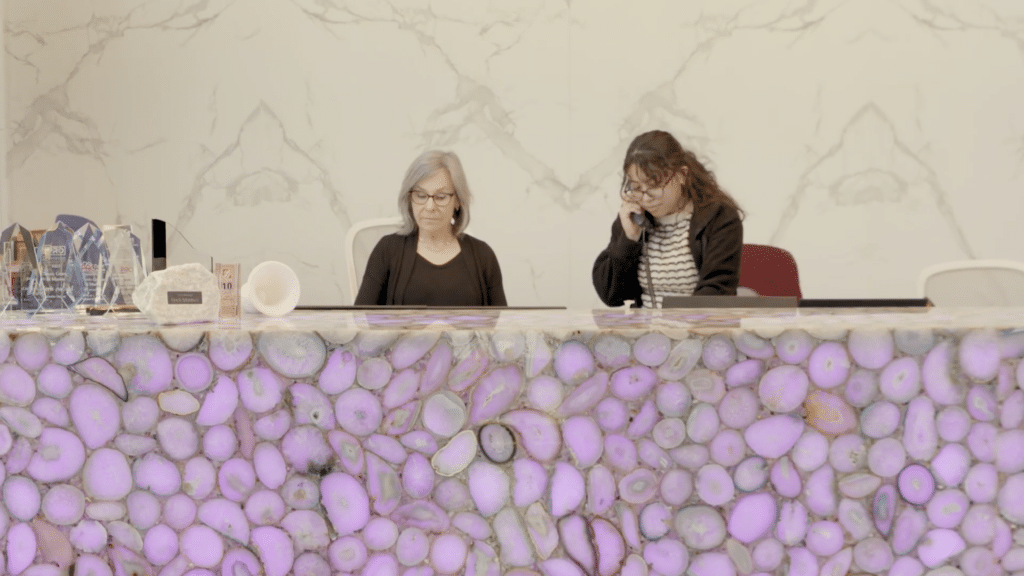 Two employees at a marble and granite company working behind an illuminated stone front desk