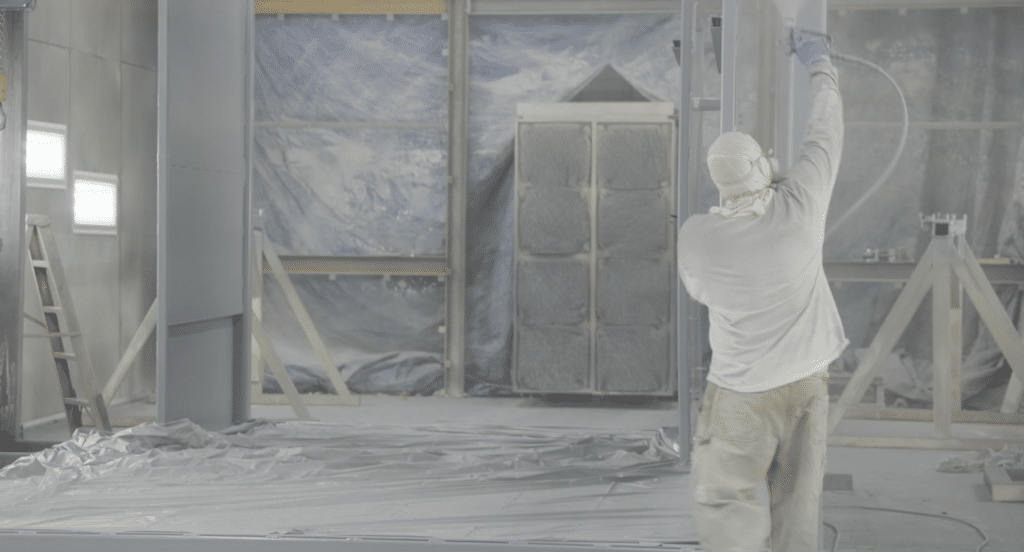 A contractor spray painting the inside of a building