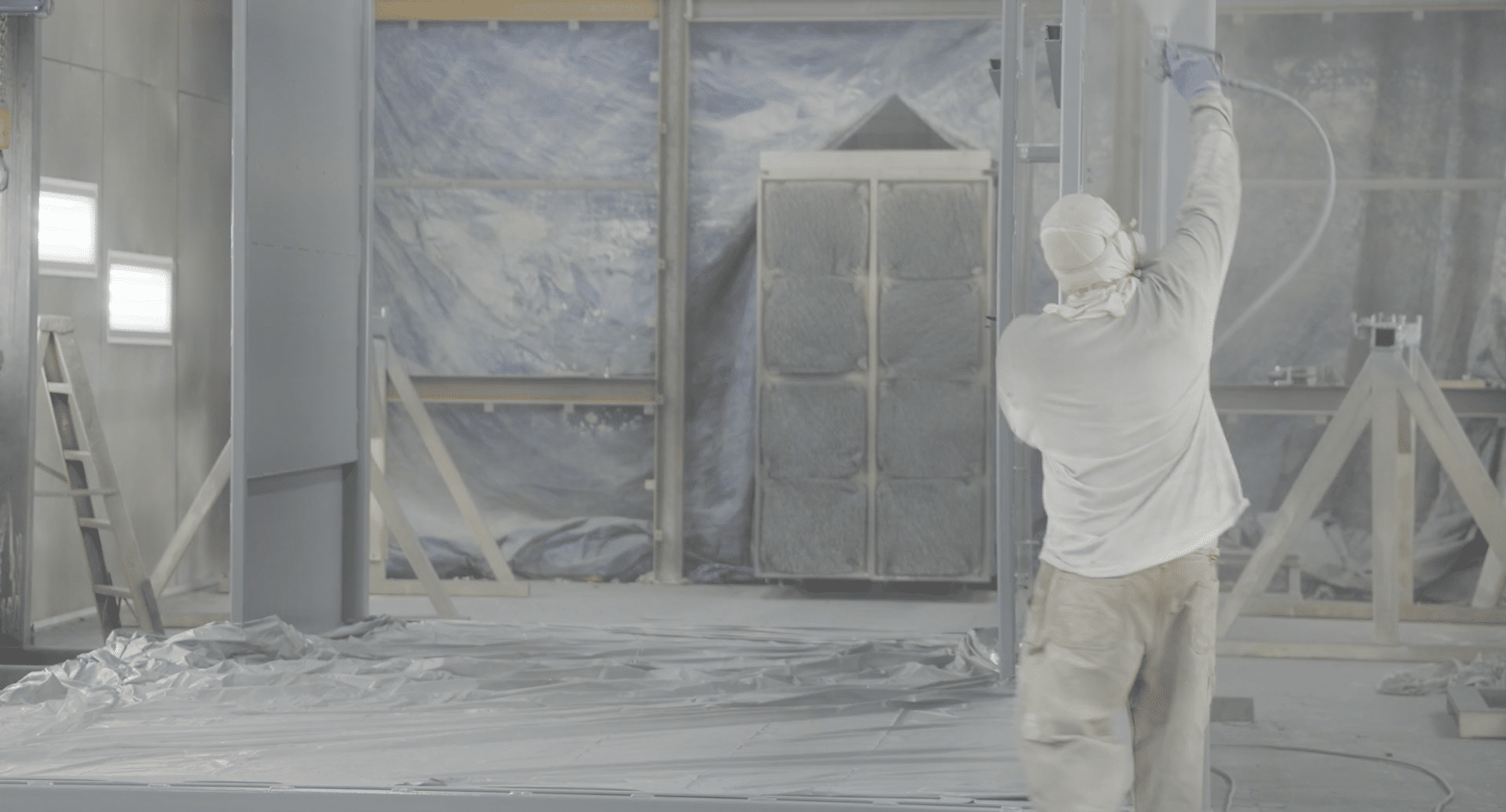 A contractor spray painting the inside of a building