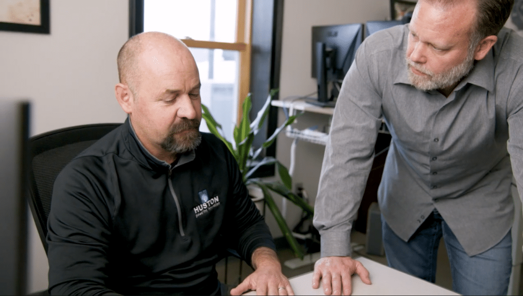 Two employees in deep conversation. One is sitting at a desk, the other is standing.