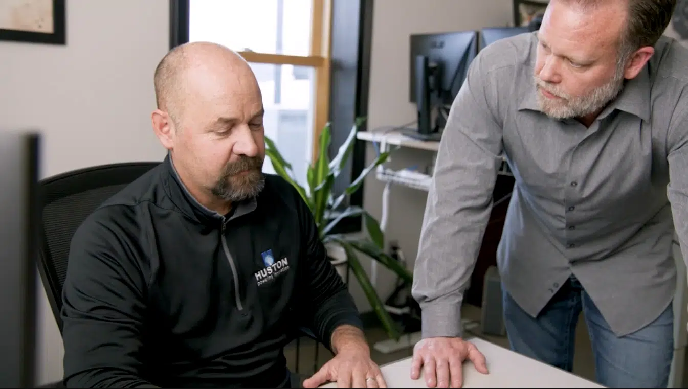 Two employees in deep conversation. One is sitting at a desk, the other is standing.