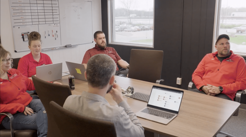 A team of employees gathered around a conference table with laptops out