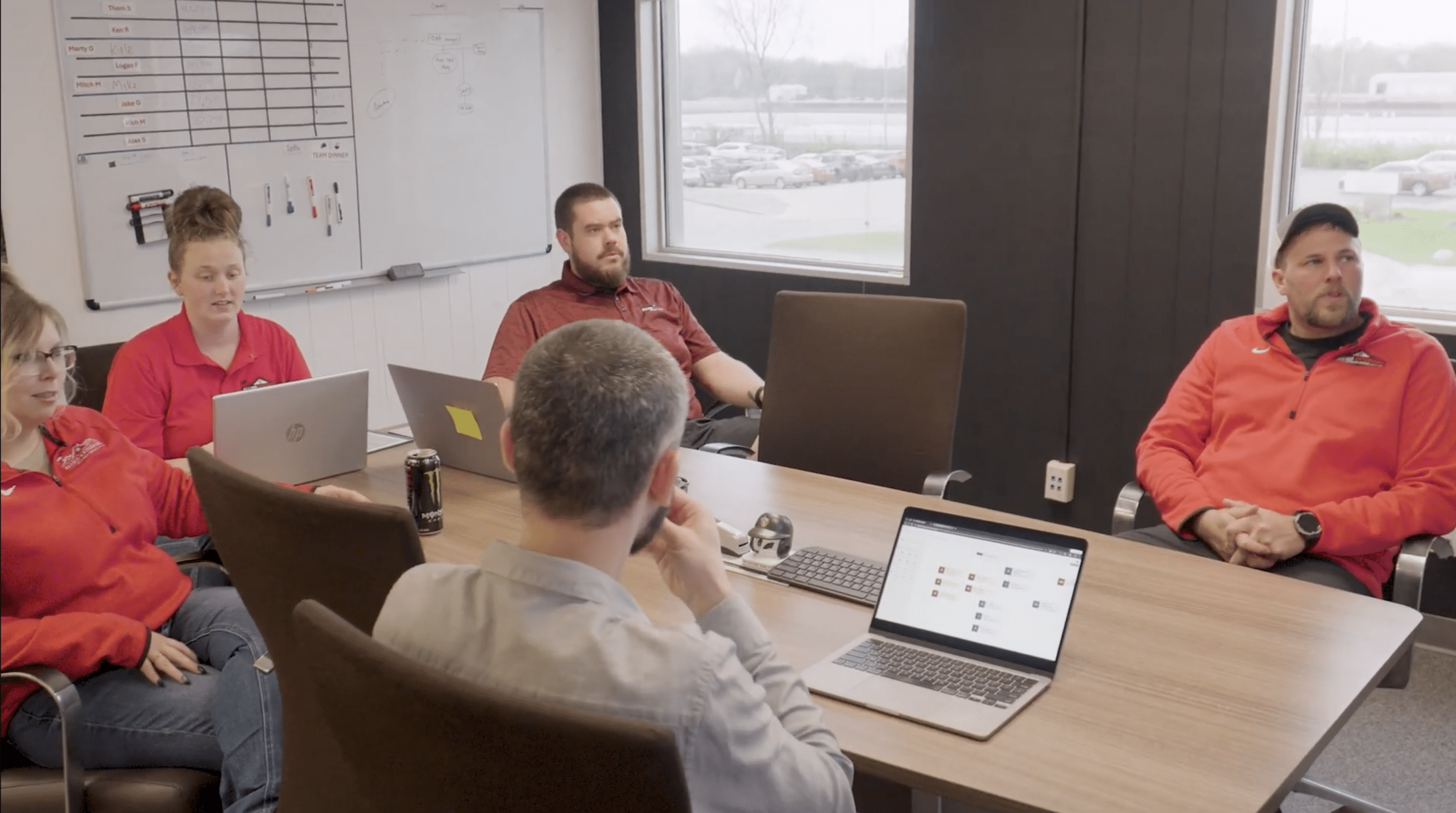 A team of employees gathered around a conference table with laptops out
