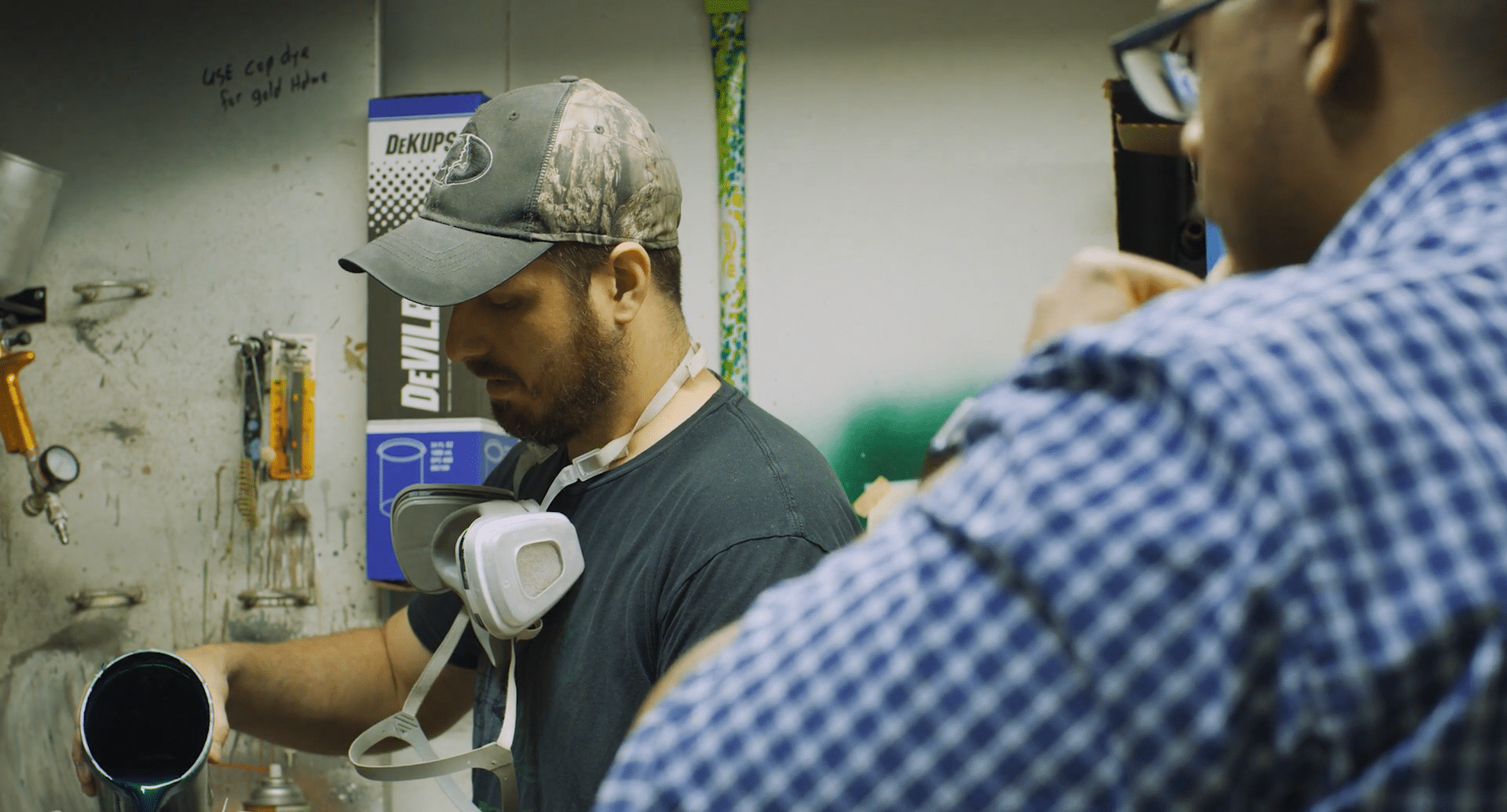 An employee pouring epoxy while his supervisor looks on