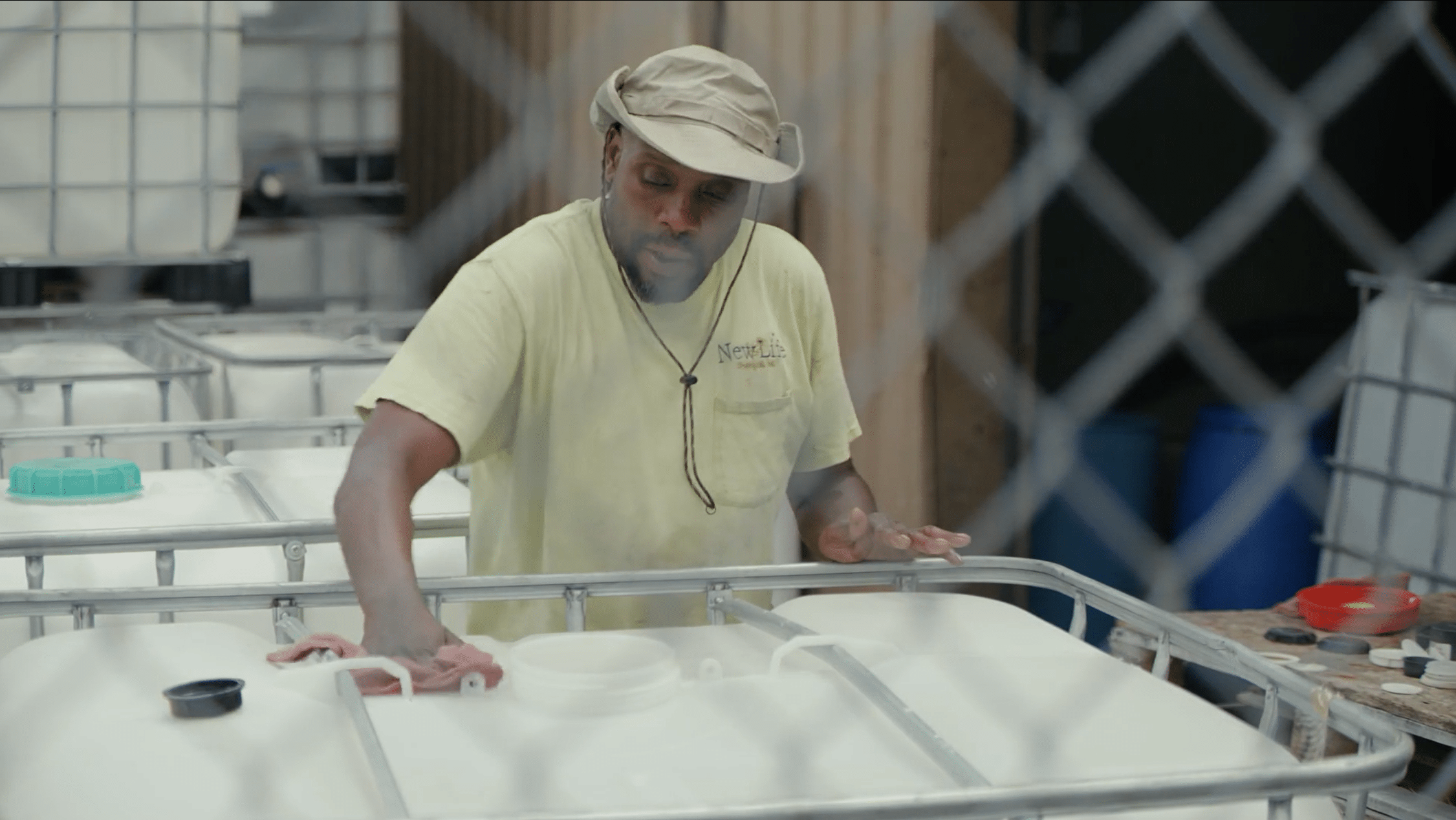 An employee at a chemical manufacturing facility wiping down a barrel.