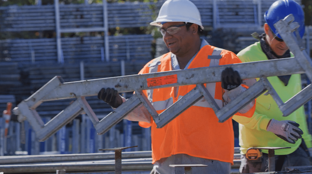 A worker in safety gear hauling scaffolding at a job site