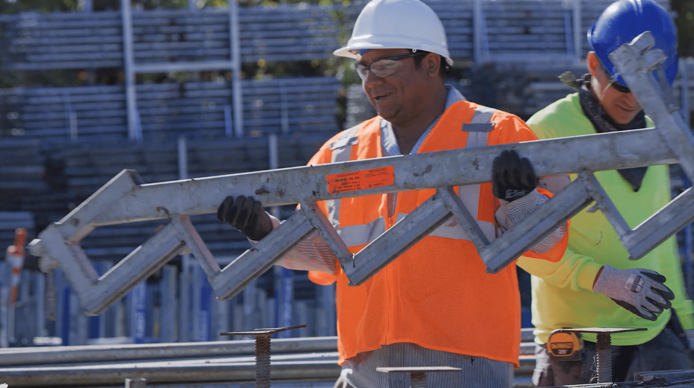 A worker in safety gear hauling scaffolding at a job site