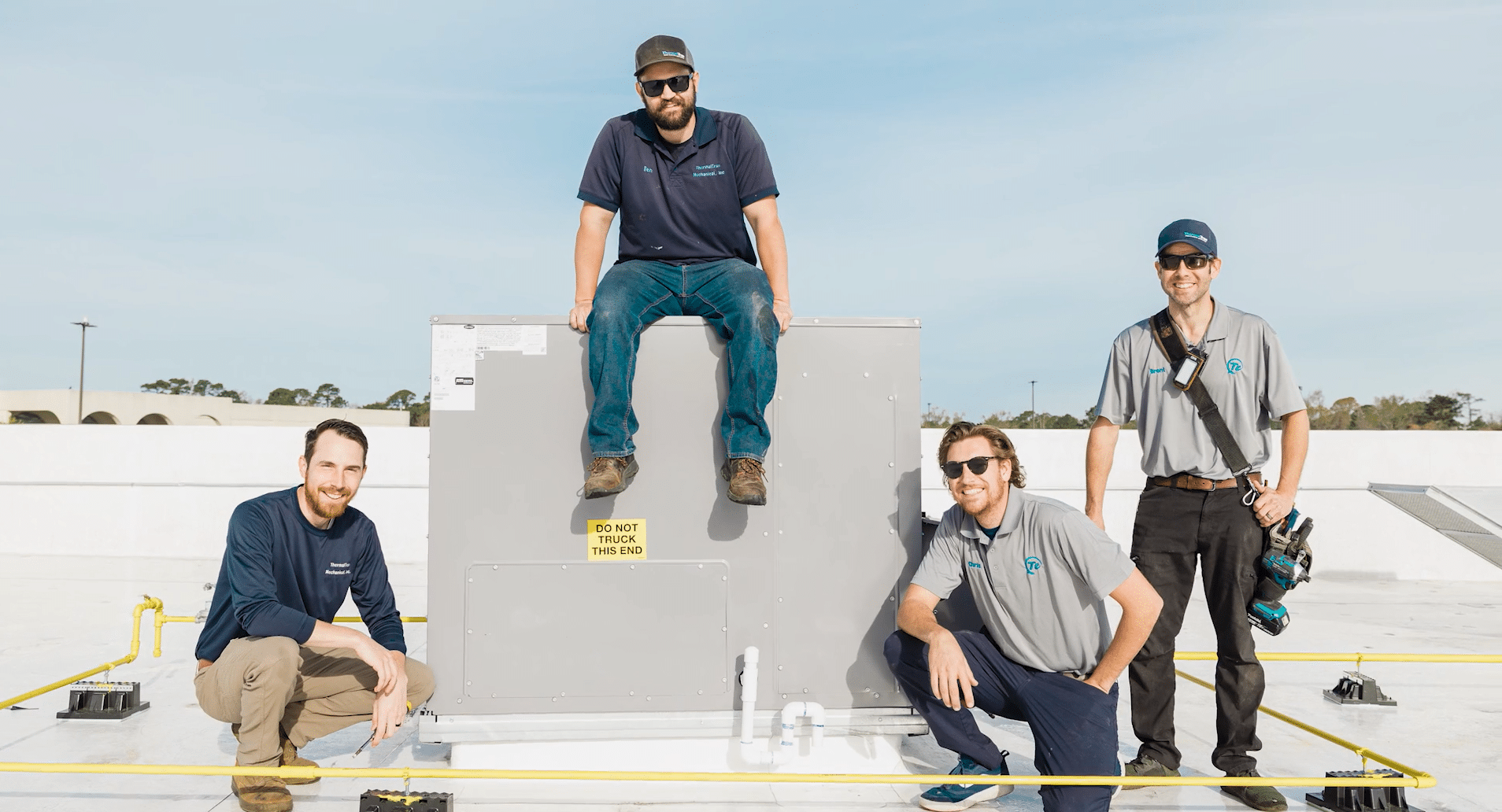 Four men posing by an HVAC system