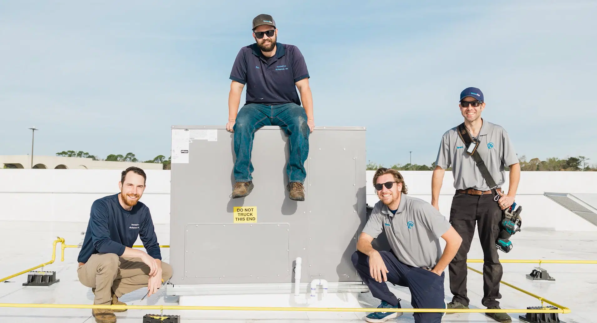 Four men posing by an HVAC system