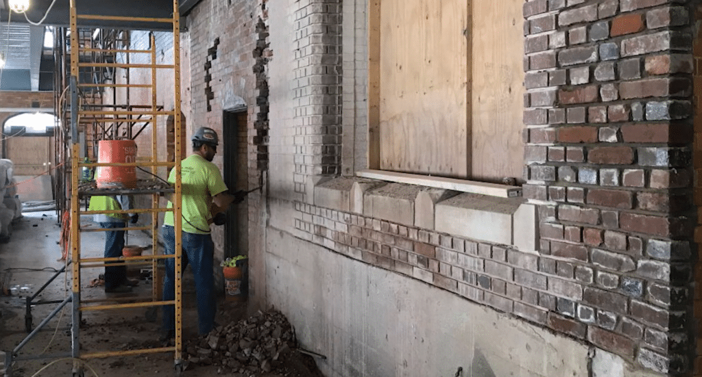 A contractor working on the brick facade of a building