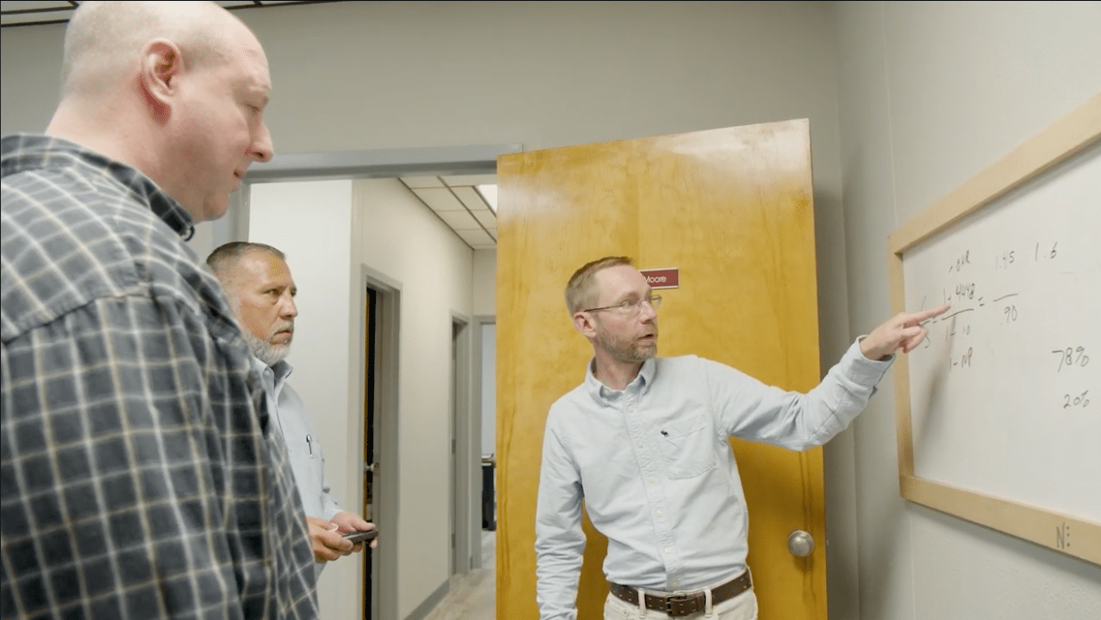 Three business leaders going over numbers on a white board
