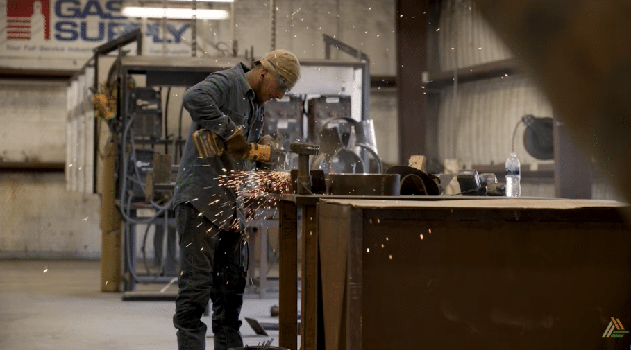 A fabricator grinding steel on the shop floor