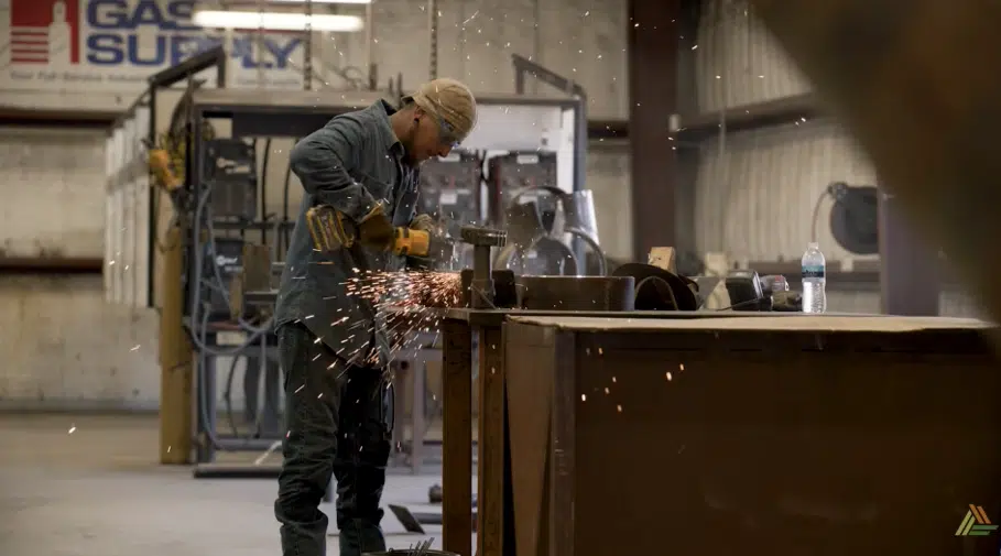 A fabricator grinding steel on the shop floor